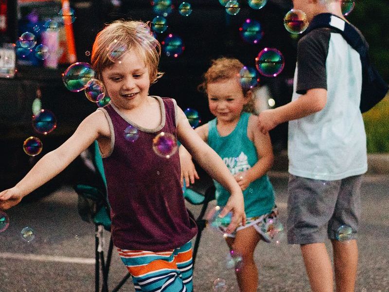Children chasing soap bubbles at an outdoor festival