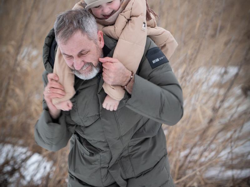 Father giving his child a shoulder ride in the winter snow
