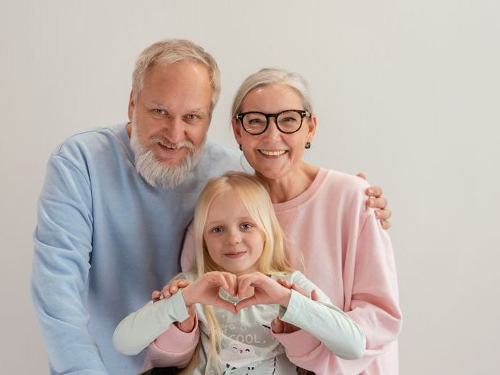 Grandparents smiling together with their granddaughter