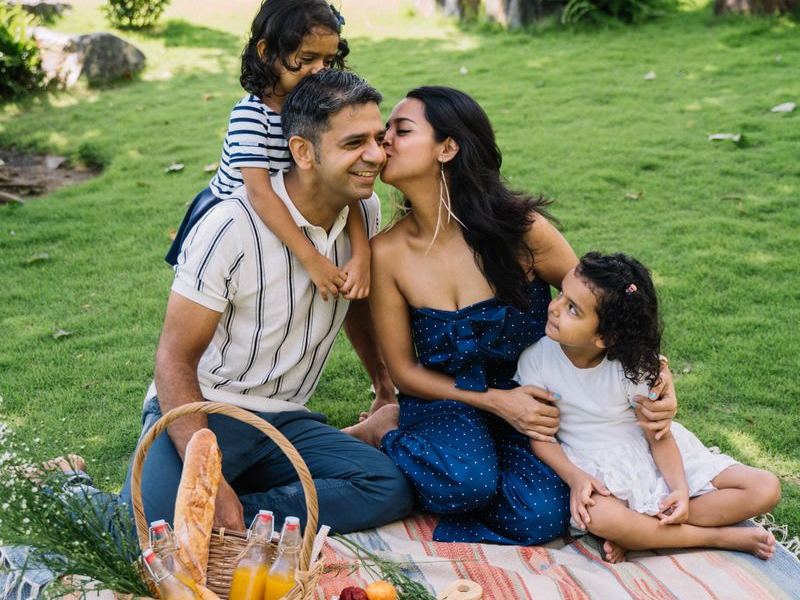 Family laughing together on a picnic blanket in a summer park