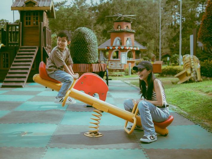 Mother and son laughing on a seesaw at an outdoor playground
