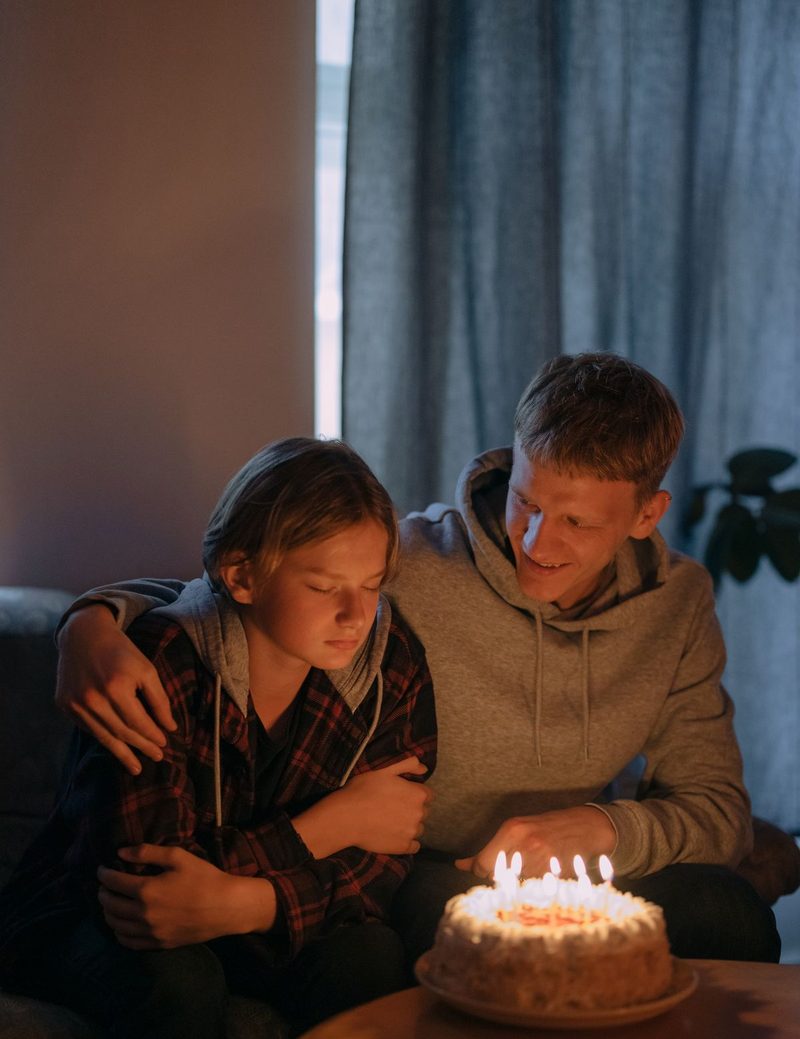 Parent and child making a wish over a birthday cake