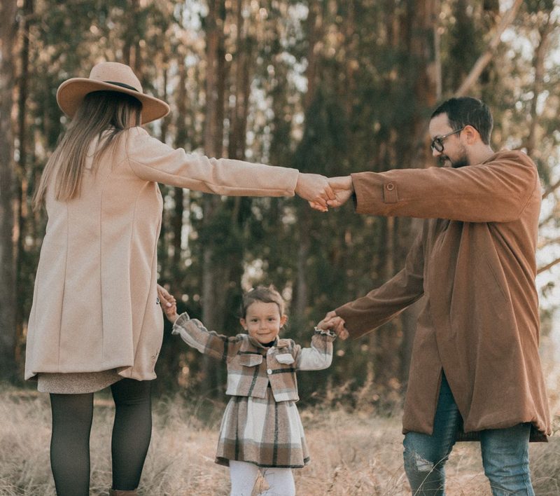 Family dancing together in a sunlit golden forest