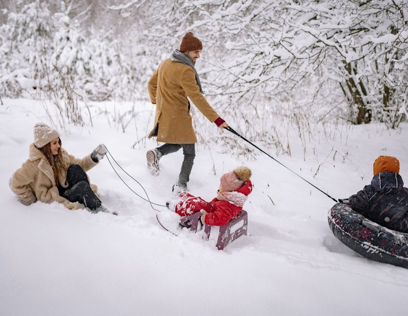 Family sledding and playing together in the snow